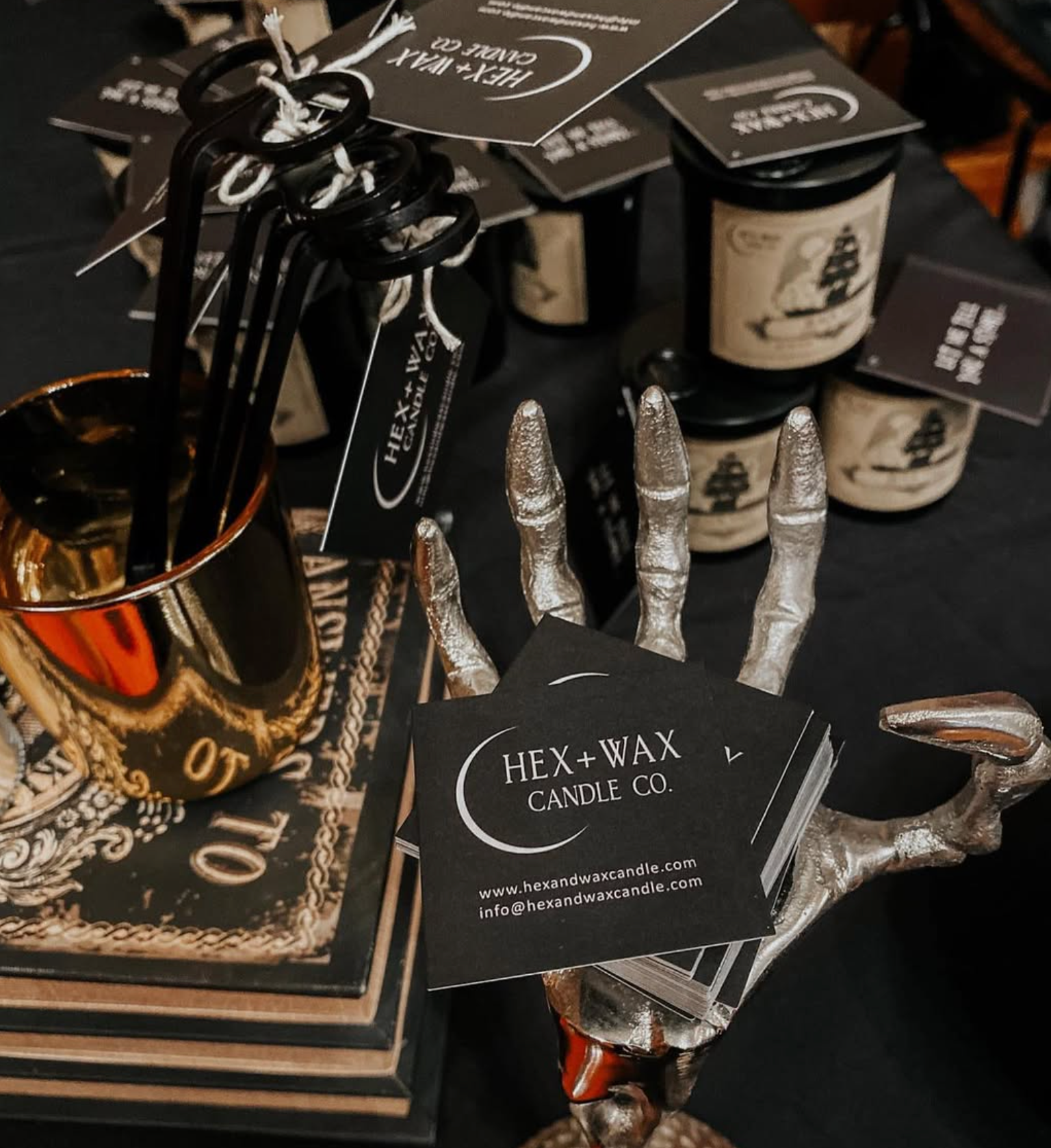 Hex and Wax candle company business cards on top of skeleton hand candle holder.